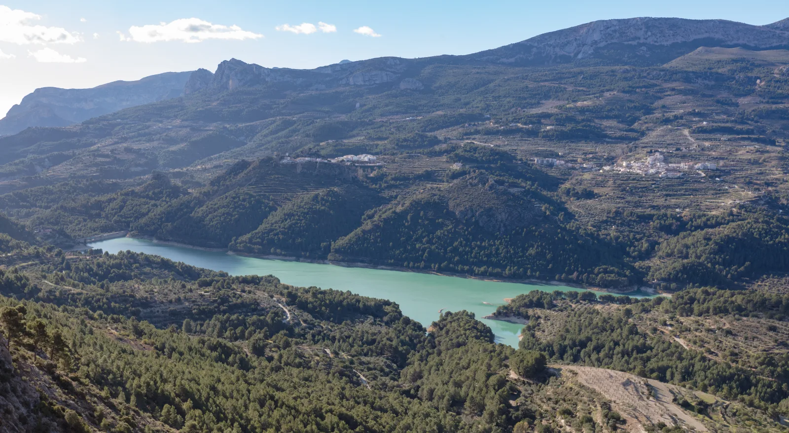 Agua azul verdosa del embalse de Guadalest entre laderas y montañas