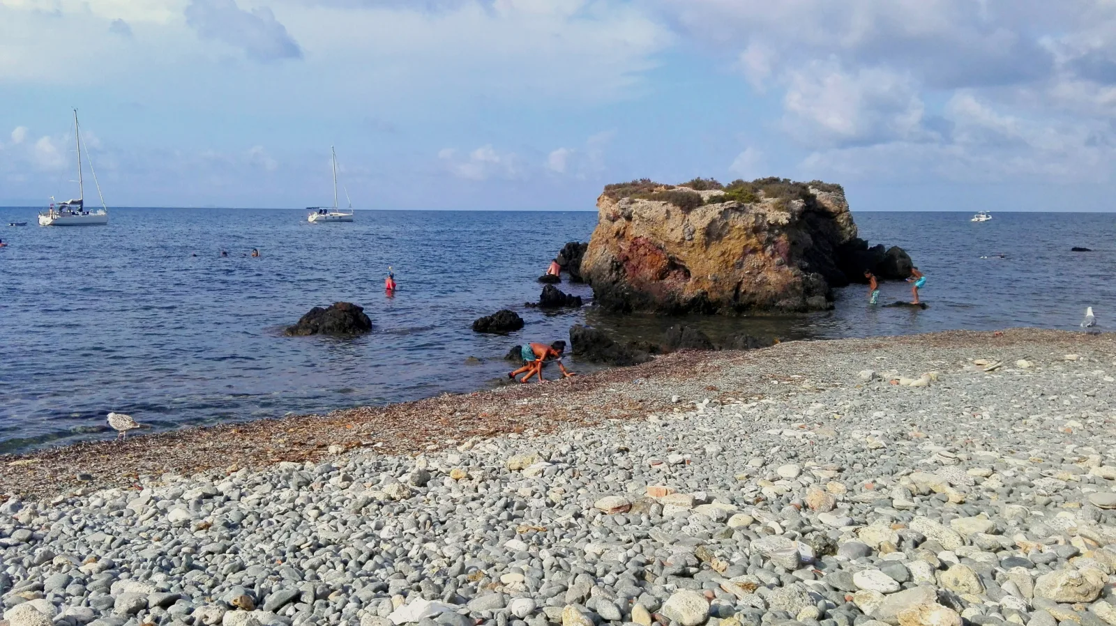 Orilla de cantos, pequeño islote rocoso y mar junto a la playa de Tabarca