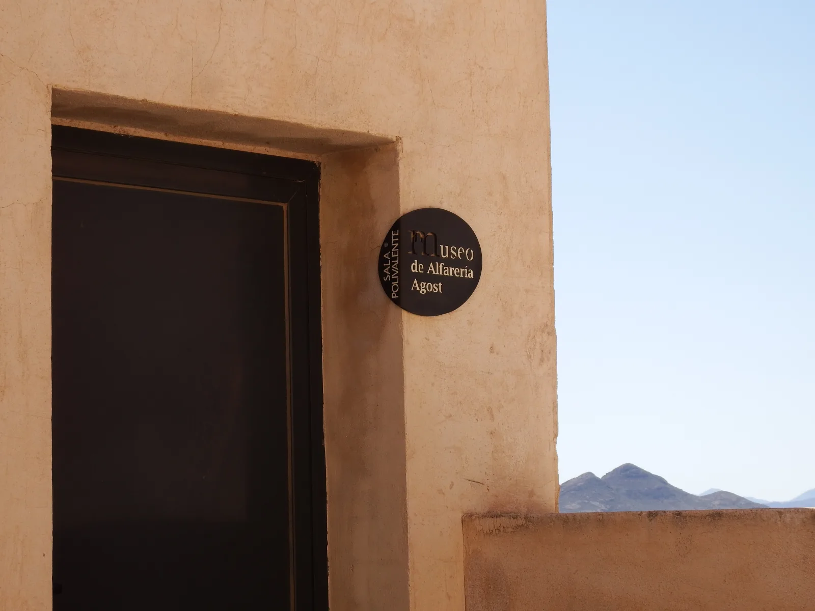 Puerta y placa del Museo de Alfarería de Agost en una fachada de tonos tierra