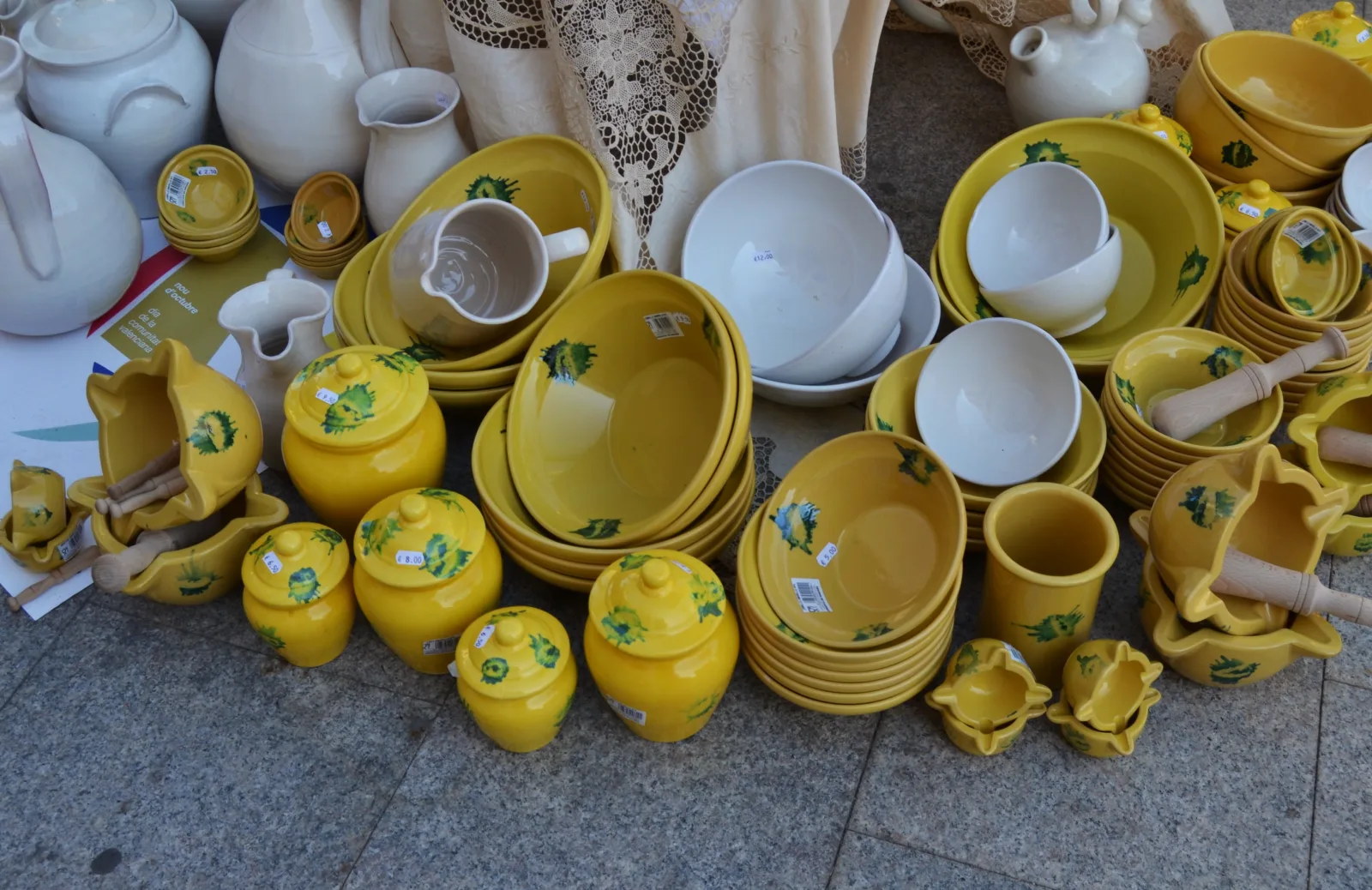 Platos, cuencos y morteros de cerámica amarilla y blanca expuestos en una feria de Gata de Gorgos
