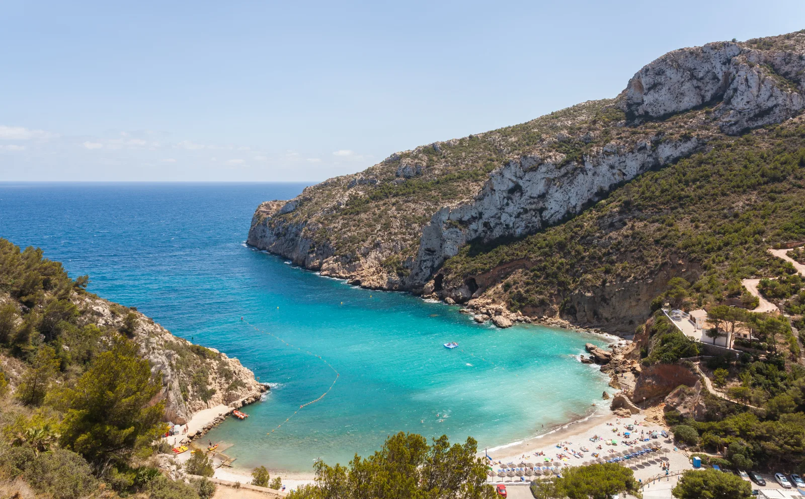 Vista elevada de la cala de la Granadella, con agua turquesa, playa y laderas de roca y pinar